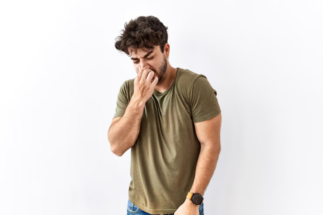 What does gas smell like: A man pinching his nose from the smell.
