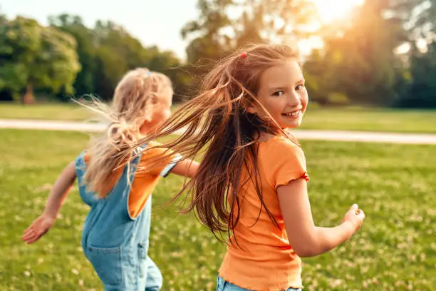 Why do heat pumps require a high amount of servicing: two blonde kids running in the park, one with an orange shirt looking to the camera.