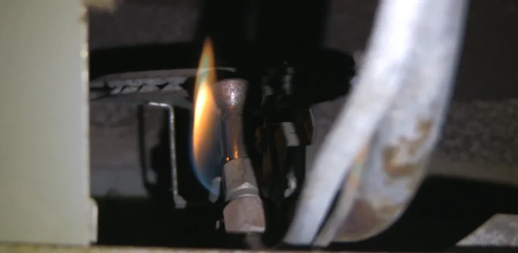 Close-up of gas furnace pilot light—faulty ignition can cause furnace smells like gas.