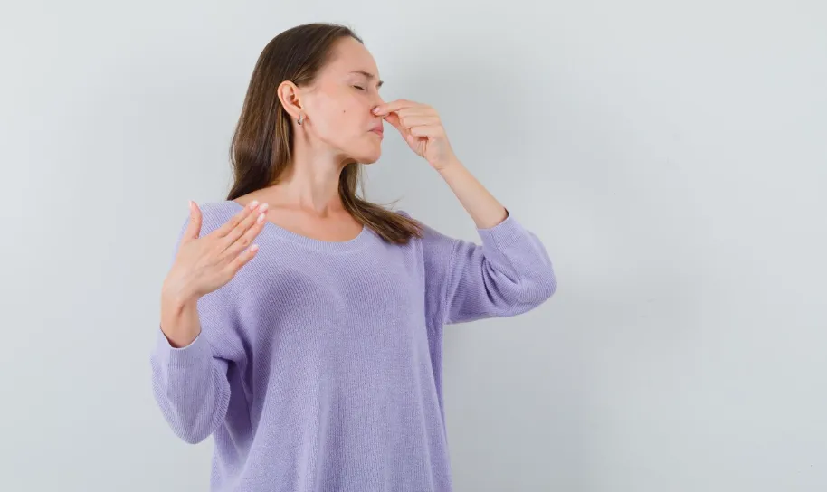 A woman pinches her nose against a sewer gas smell in the house.