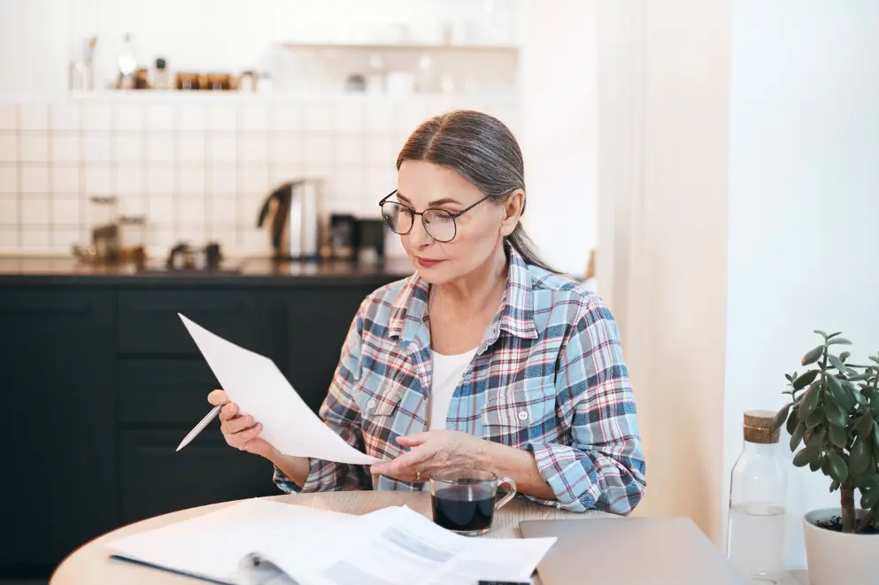 A woman reads quotes from different plumbers for her gas hot water replacement
